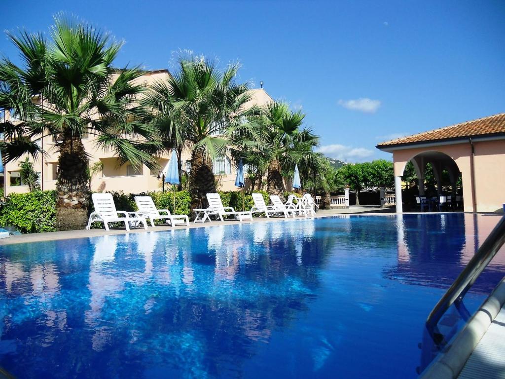 una piscina con sillas blancas y palmeras en Apartment Laura-2 by Interhome, en Castellammare di Velia