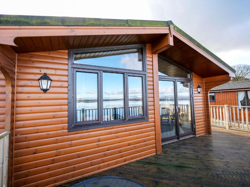 a log cabin with windows and a balcony at Chalet Loch Leven Lodge by Interhome in Ballingry