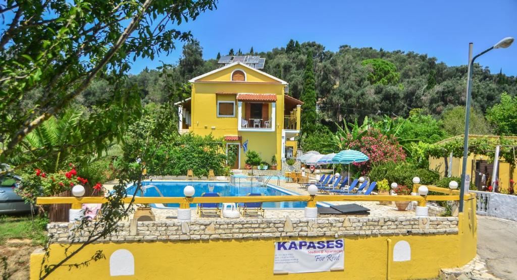 a yellow house with a swimming pool in front of it at Kapases Studios & Apartments in Peroulades