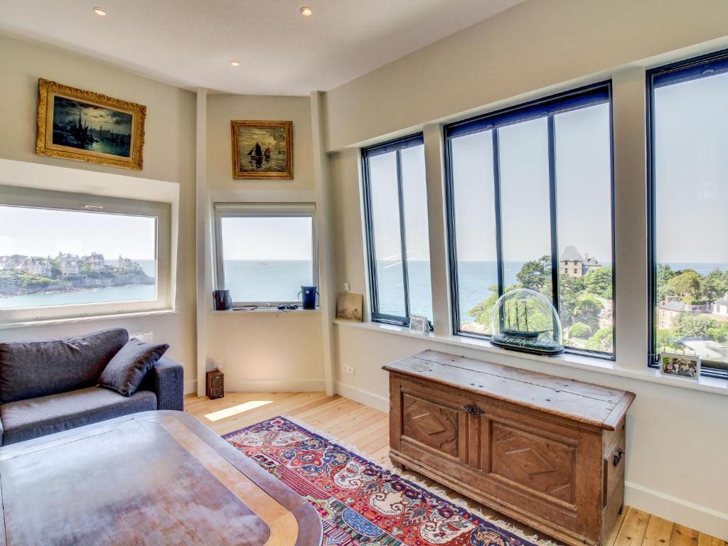 a living room with a couch and a table and windows at Apartment Château des Deux Rives by Interhome in Dinard