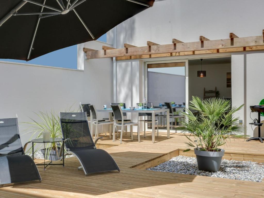 eine Terrasse mit Tisch und Stühlen und einem Sonnenschirm in der Unterkunft Apartment Les Patios de Flore-1 by Interhome in Mimizan-Plage