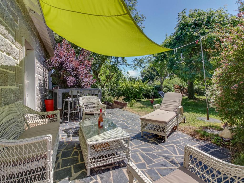 een patio met stoelen en een tafel met een groene parasol bij Holiday Home La Roche Blanche by Interhome in Port Blanc