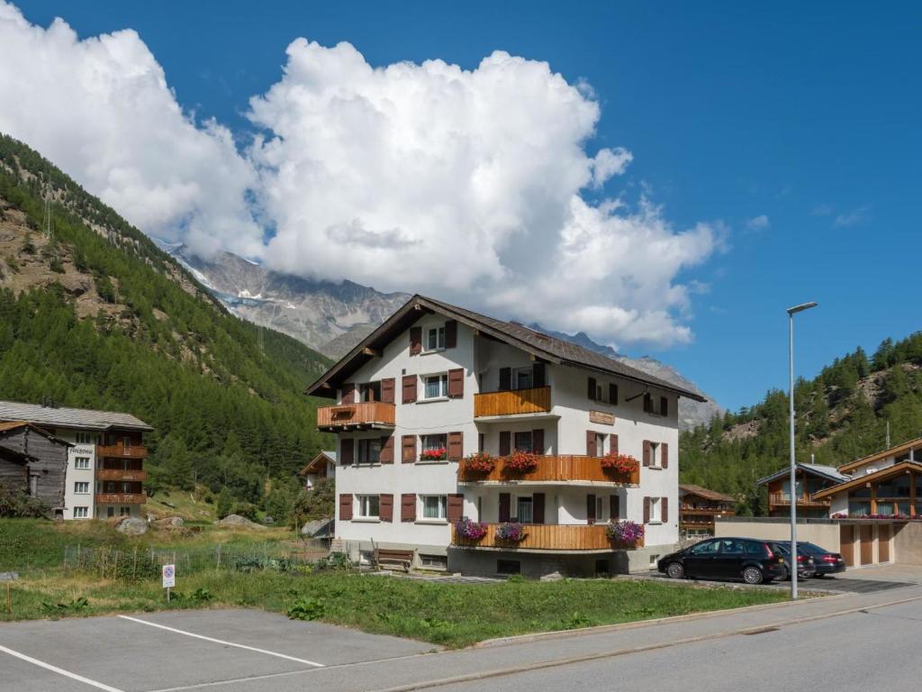 a building in a parking lot next to a mountain at Apartment Haus Bergsonne by Interhome in Saas-Almagell