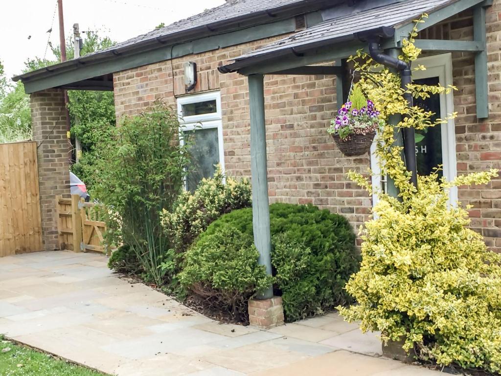 a brick house with a pergola and plants at Holiday Home Woodhouse-5 by Interhome in Shermanbury