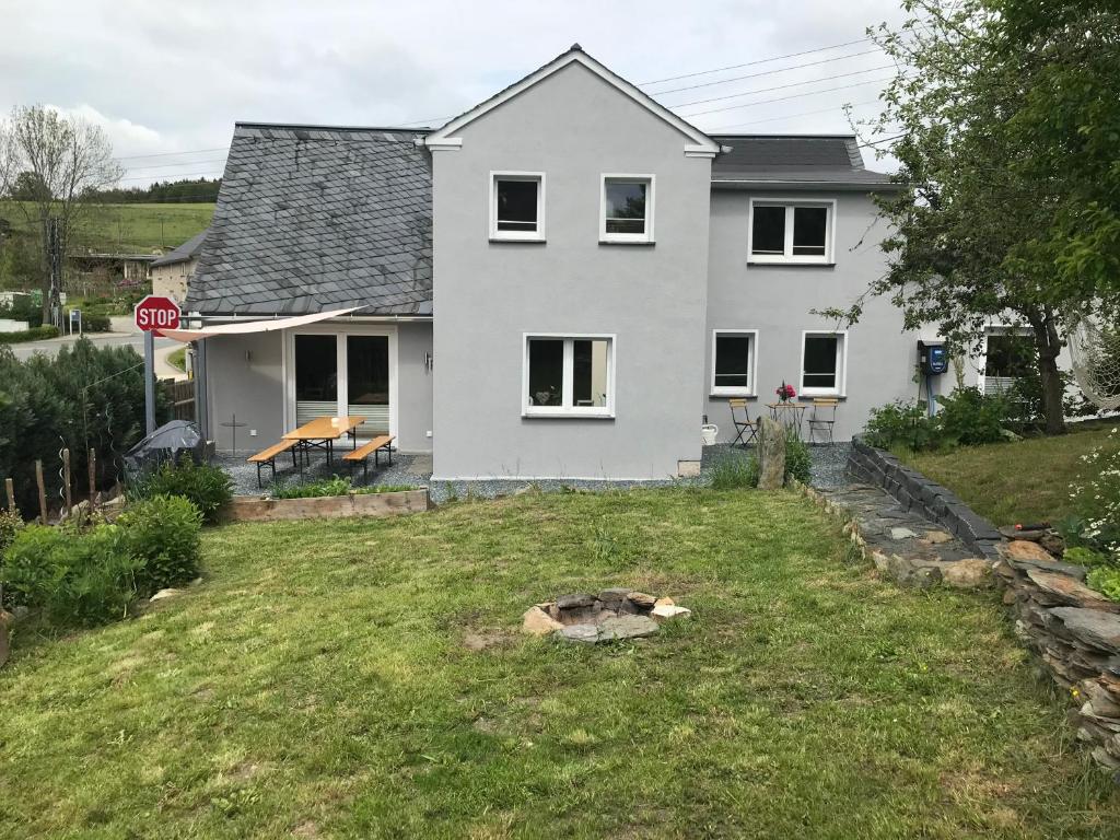 a white house on a hill with a stop sign at Pension Schneidenbach in Reichenbach im Vogtland