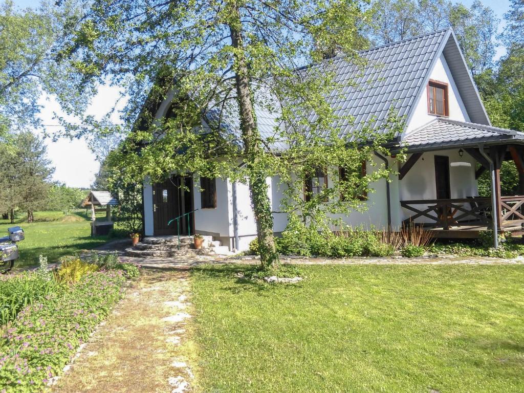 une maison blanche avec un arbre dans la cour dans l'établissement Holiday Home Zatylówka by Interhome, à Zatyle