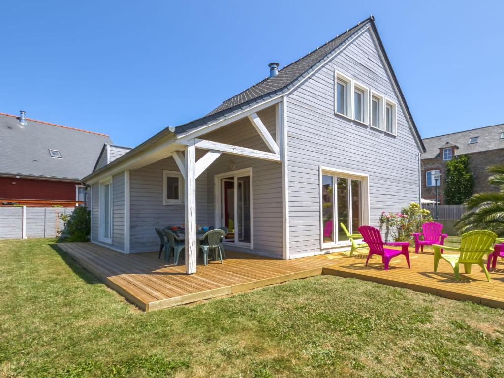 a house with a deck with chairs and a table at Holiday Home Pen-Guen by Interhome in Dinard