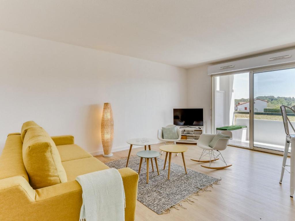 een woonkamer met een gele bank en een tafel bij Apartment Le clos Xapella by Interhome in Bidart