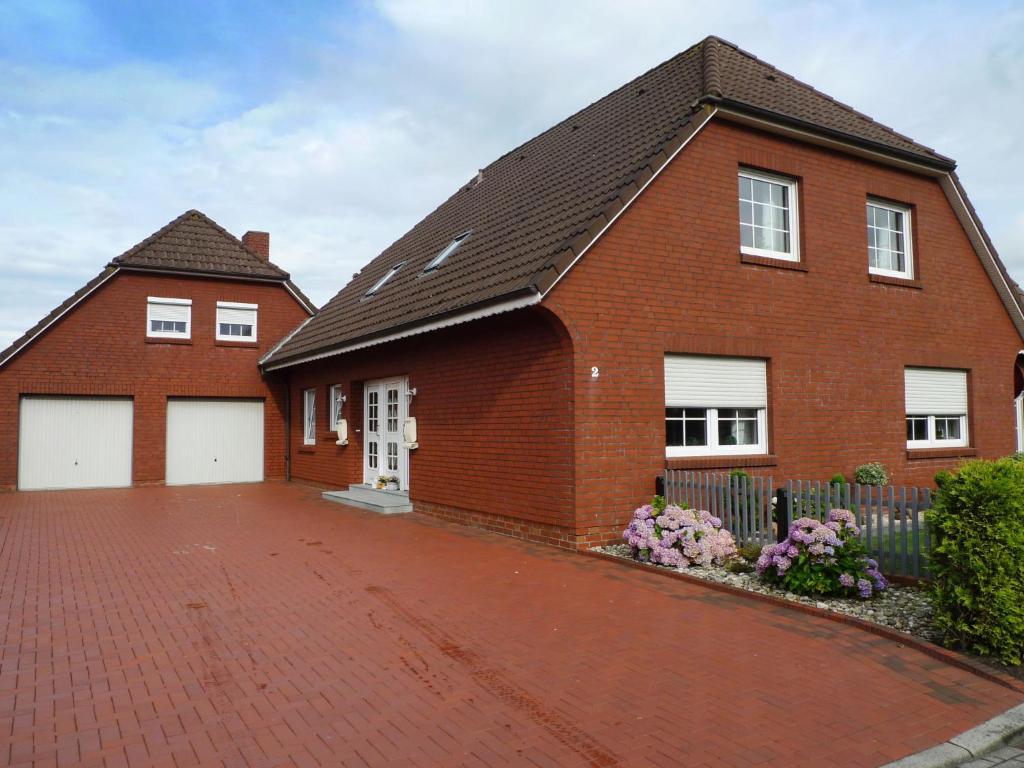 ein rotes Backsteinhaus mit zwei weißen Garagentüren in der Unterkunft Apartment Alina by Interhome in Marienhafe