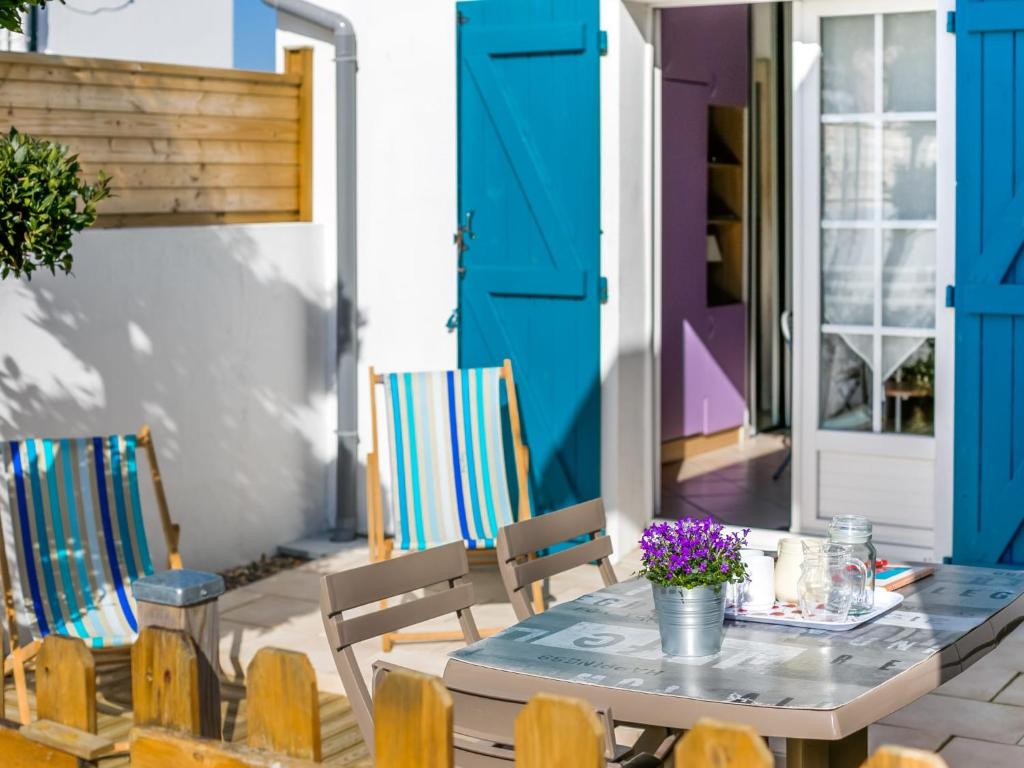 una mesa y sillas en un patio con puertas azules en Studio Etxe Tikia, en Guéthary