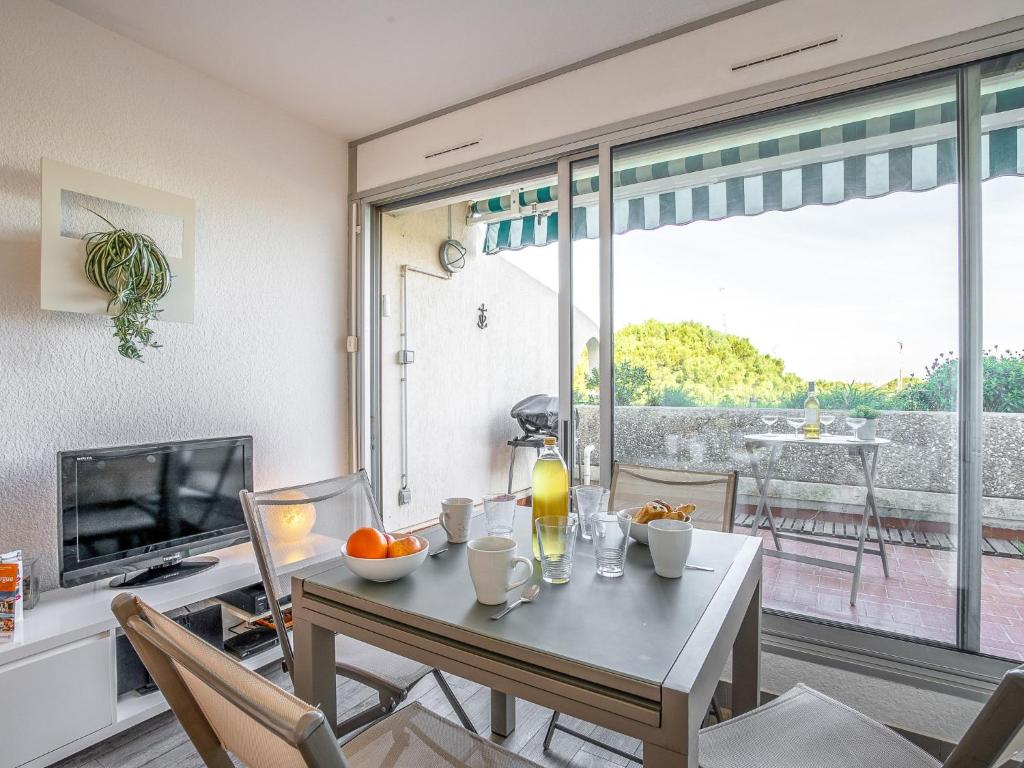 une salle à manger avec une table et une télévision dans l'établissement Apartment Le Quai aux Fleurs-5 by Interhome, au Grau-du-Roi