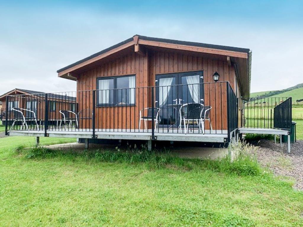 eine große Holzhütte mit Stühlen und Tischen in der Unterkunft Chalet Loch Leven Lodge 6 by Interhome in Kinross