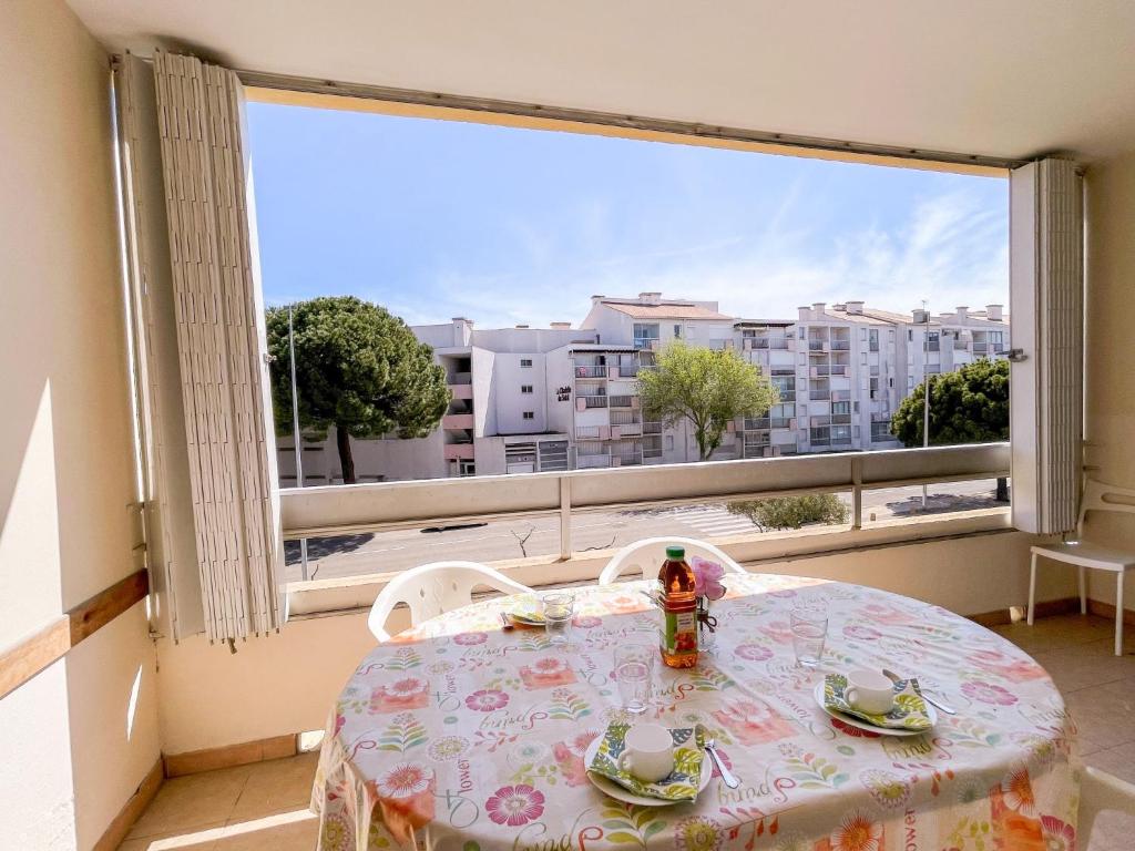 einen Tisch und Stühle in einem Zimmer mit einem großen Fenster in der Unterkunft Apartment Floralies I-5 by Interhome in Le Grau-du-Roi