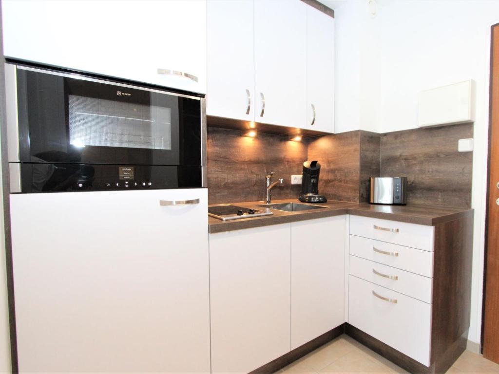 a white kitchen with a microwave and a refrigerator at Apartment Alpenland-22 by Interhome in Seefeld in Tirol