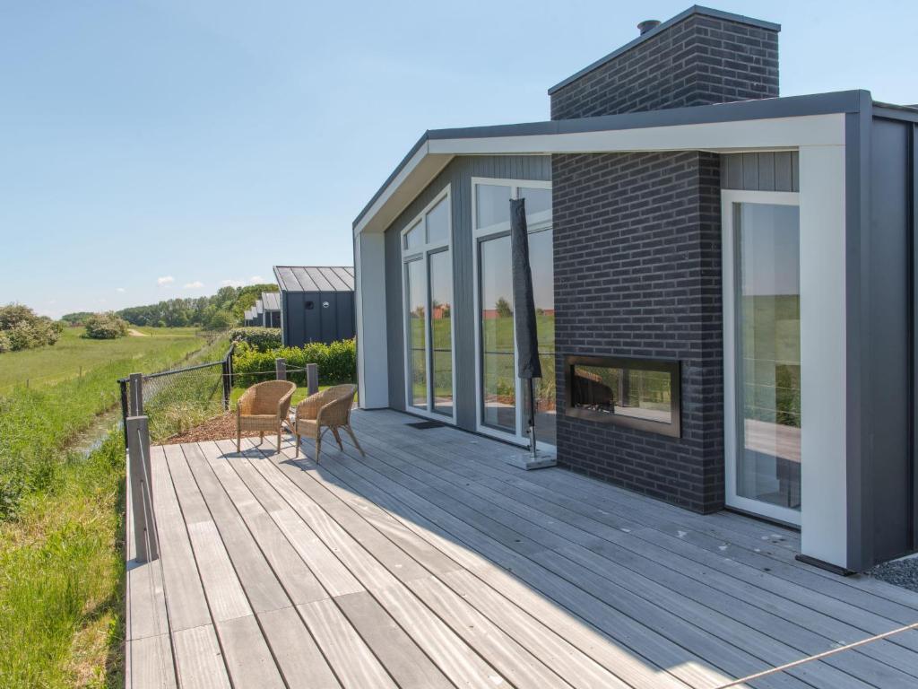 a wooden deck with two chairs and a fireplace at Holiday Home Ruisweg 59 by Interhome in Wemeldinge