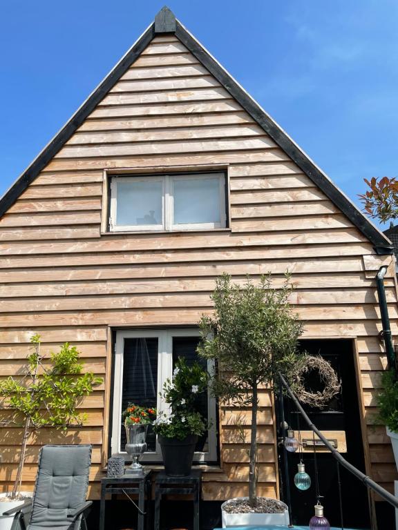 une maison avec un toit en gambrel et une terrasse dans l'établissement Tiny House Lindenhouse, à Heemstede