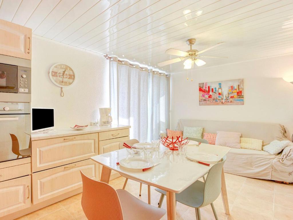 une cuisine et un salon avec une table et des chaises blanches dans l'établissement Apartment Les Portes de la Plage by Interhome, à Gruissan