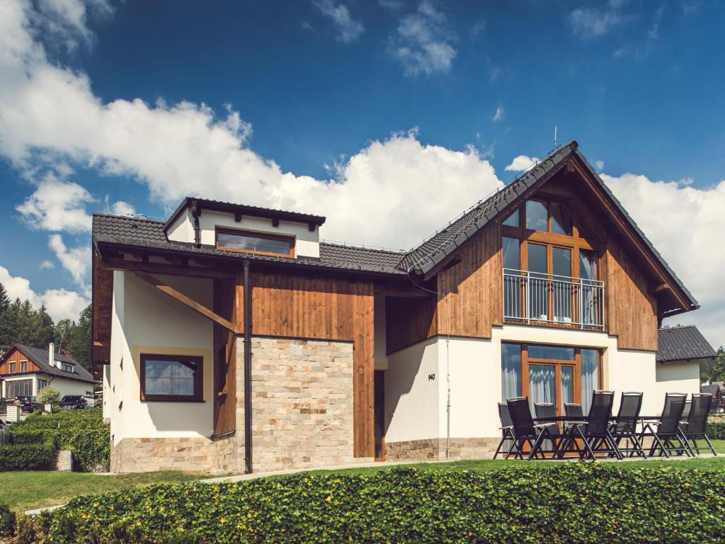 een huis met stoelen ervoor bij Holiday Home Residence Lipno by Interhome in Lipno nad Vltavou