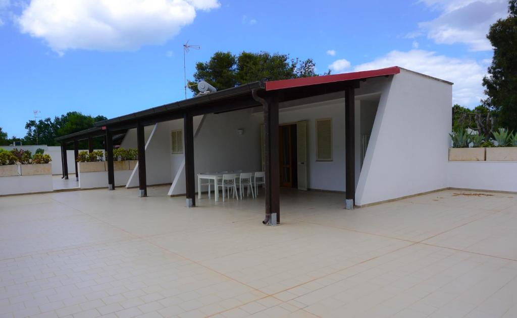 a white building with a red roof and a patio at Sand Lily Apartment in Ugento