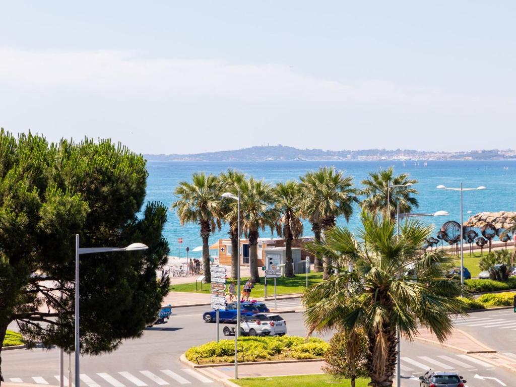 Elle offre une vue sur une rue bordée de palmiers et l'océan. dans l'établissement Apartment L'Auteuil by Interhome, à Cagnes-sur-Mer