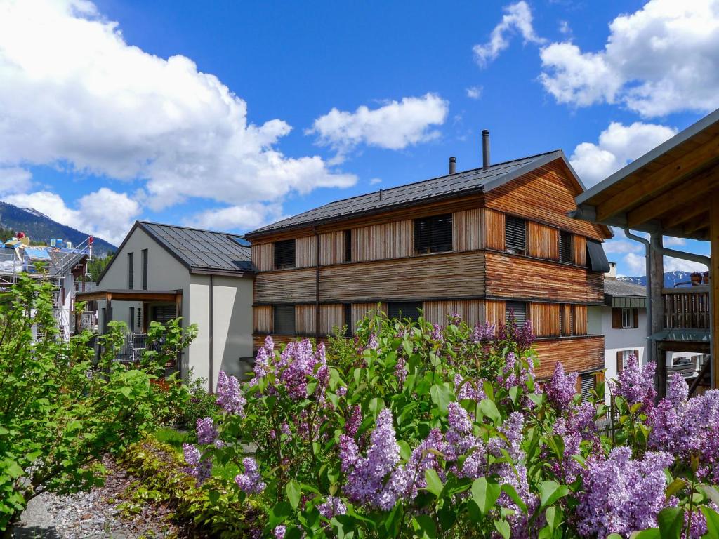 ein Holzhaus mit lila Blumen davor in der Unterkunft Apartment Bergidyll by Interhome in Flims