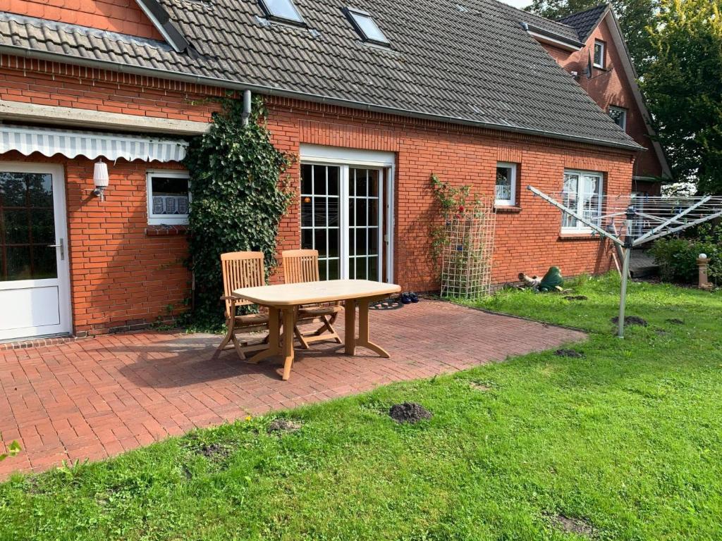 a wooden table and chairs in front of a brick house at Apartment Osterkamp by Interhome in Eversmeer