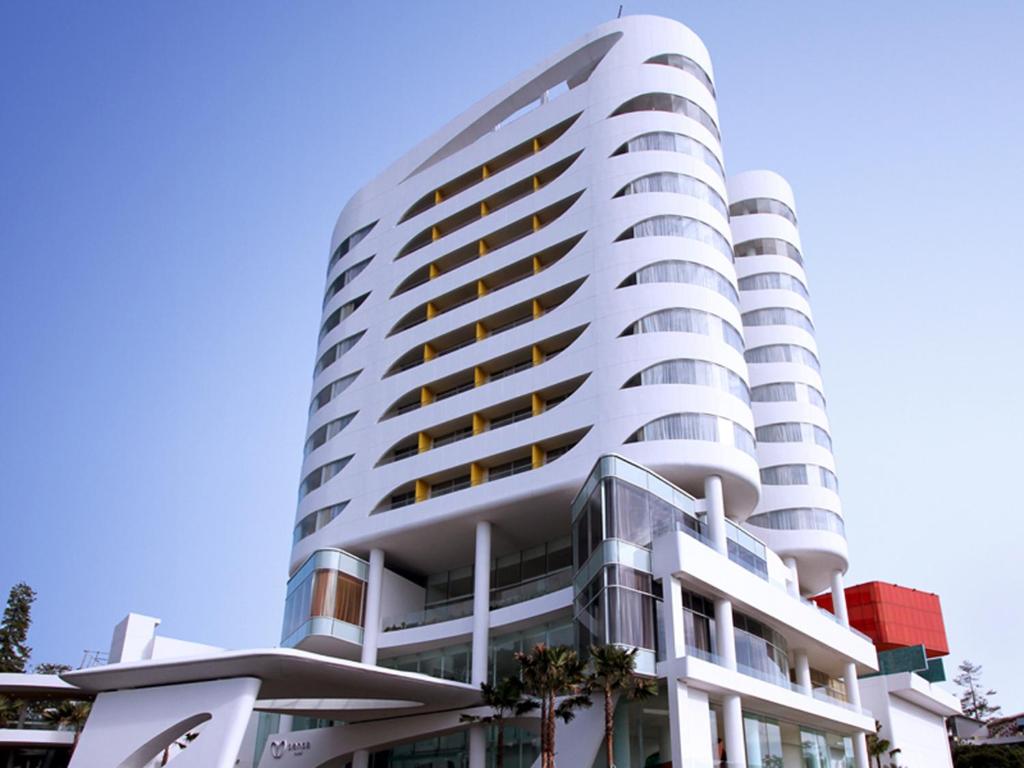 un alto edificio bianco con alberi di fronte di Sensa Hotel Bandung a Bandung