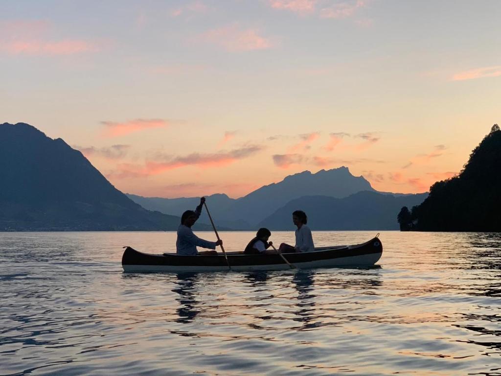 trzy osoby w kajaku na wodzie o zachodzie słońca w obiekcie Ferienwohnungen mit 4 Betten in Gersau direkt am Vierwaldstättersee w mieście Gersau