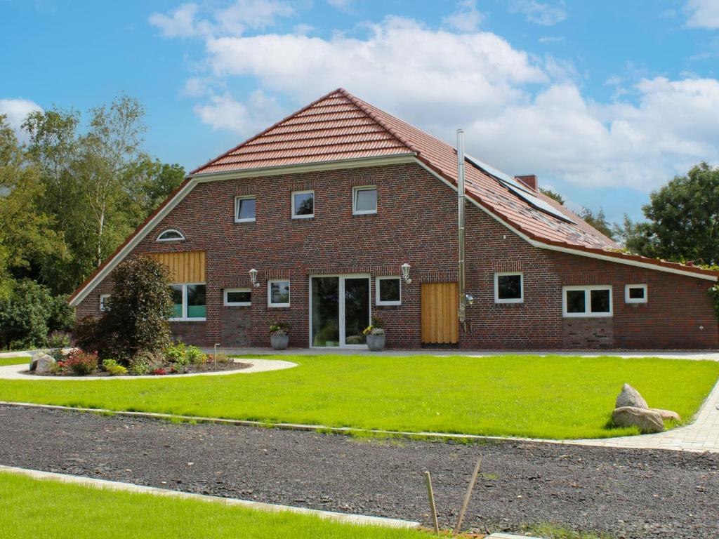 een rood bakstenen huis met een grasveld bij Apartment Langeoog by Interhome in Westerholt