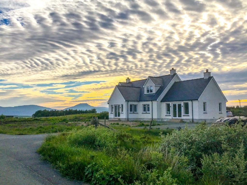 a house in a field with a cloudy sky at Villa Ruadh by Interhome in Ose