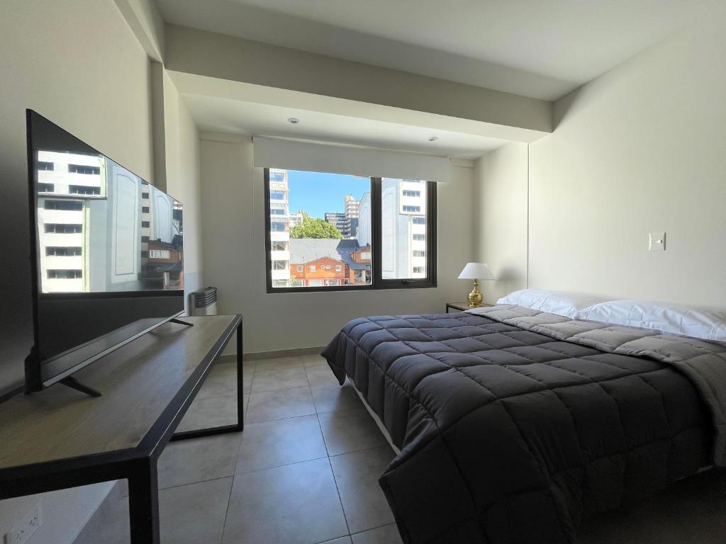 een slaapkamer met een bed en een flatscreen-tv bij Departamento Céntrico Bariloche in Bariloche