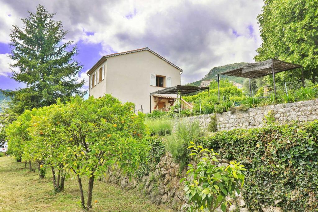 a house behind a stone wall with trees in front of it at LOCATIONS-06 La Maison de Noelie garden floor in Le Bar-sur-Loup