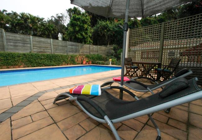 einen Liegestuhl und einen Sonnenschirm neben einem Pool in der Unterkunft Bayete Self Catering in Durban