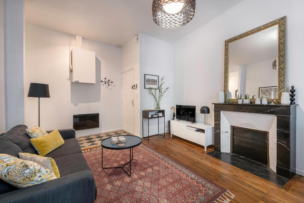 ein Wohnzimmer mit einem Sofa und einem Kamin in der Unterkunft Chaleureux appartement pour 5 à deux pas de la Place Graslin in Nantes