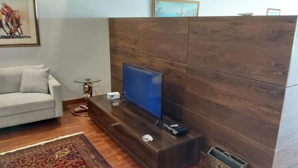 a living room with a tv on a wooden wall at The Polo Residence, Lahore, Near Allama Iqbal International Airport (Apartment) in Lahore