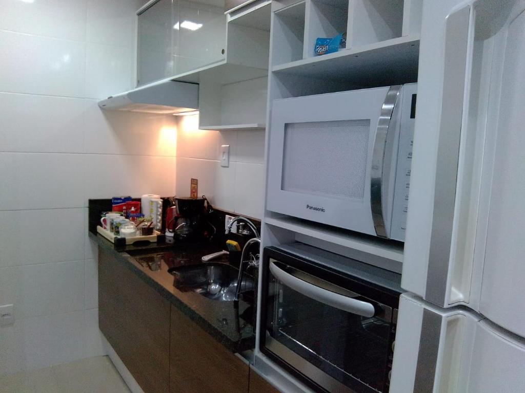 uma cozinha com um micro-ondas e um lavatório em Apartamento completo A42 Flat Centro em Mogi das Cruzes