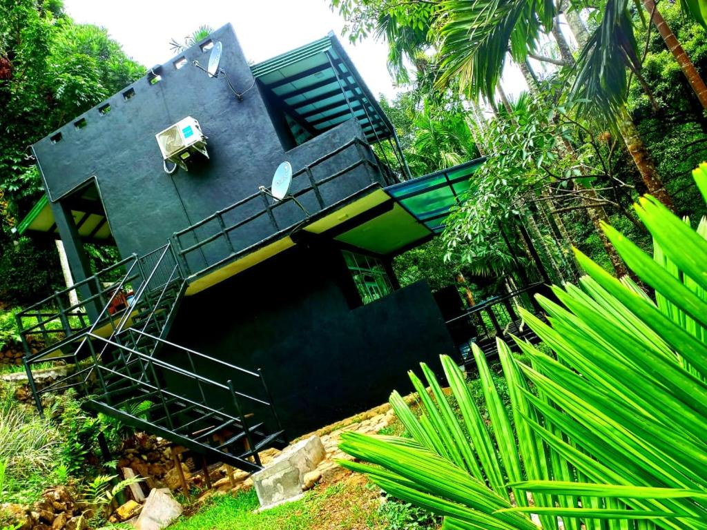 una casa negra con una escalera que conduce a ella en Cool Garden belihuloya, en Belihuloya