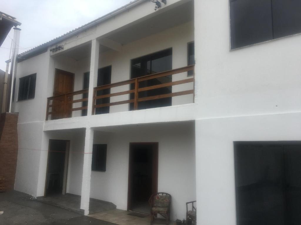 un edificio blanco con balcón y silla en Casa de aluguel Gregório, en Imbituba