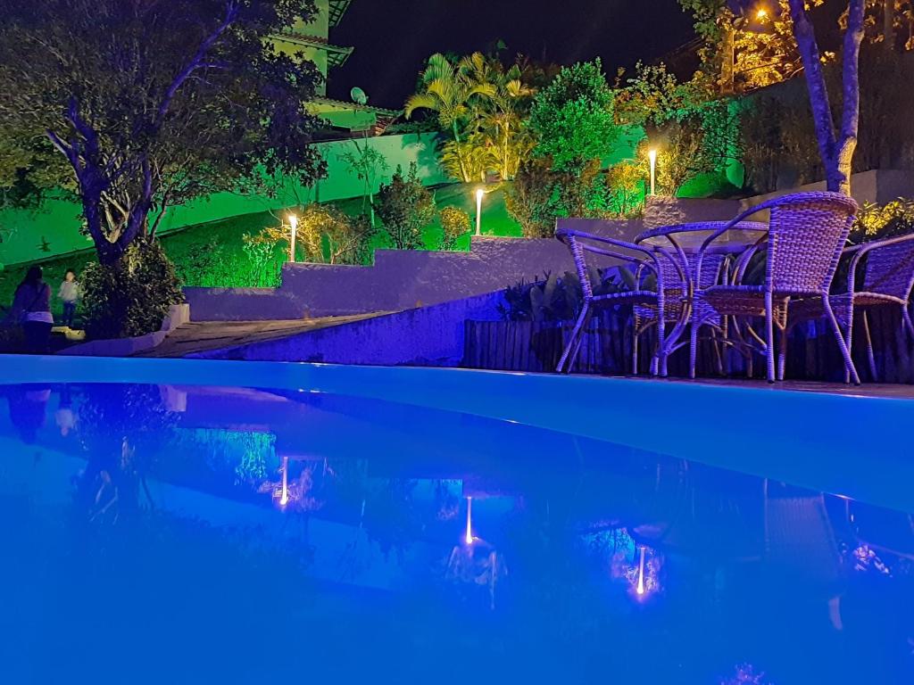 a pool at night with purple chairs and lights at Condomínio Solar João Fernandes in Búzios