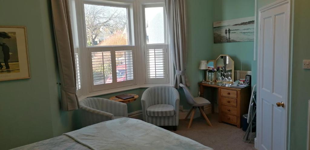 a bedroom with a bed and a desk and a window at Pebbles House in Seaton