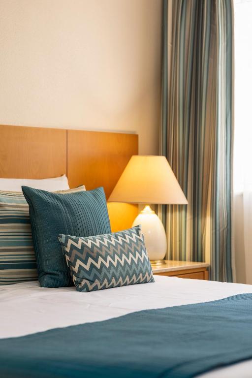 a bedroom with a bed with blue pillows and a lamp at Interpass Vau Hotel Apartamentos in Portimão