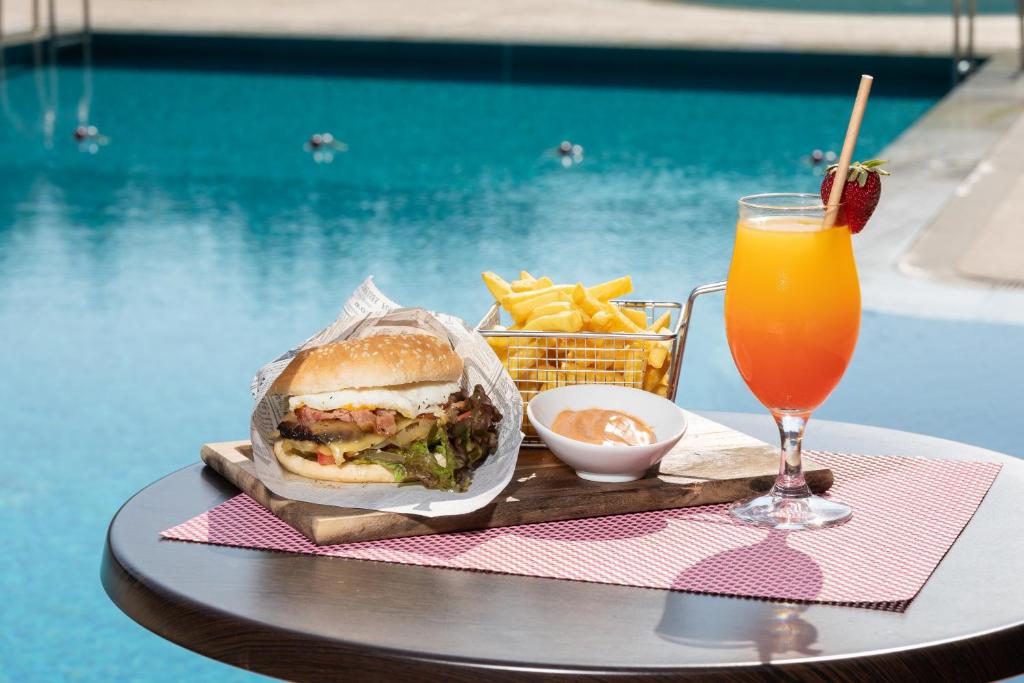 a sandwich and french fries and a drink on a table at Interpass Vau Hotel Apartamentos in Portimão