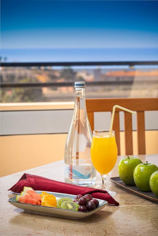 a bottle of juice and a plate of fruit on a table at Interpass Vau Hotel Apartamentos in Portimão