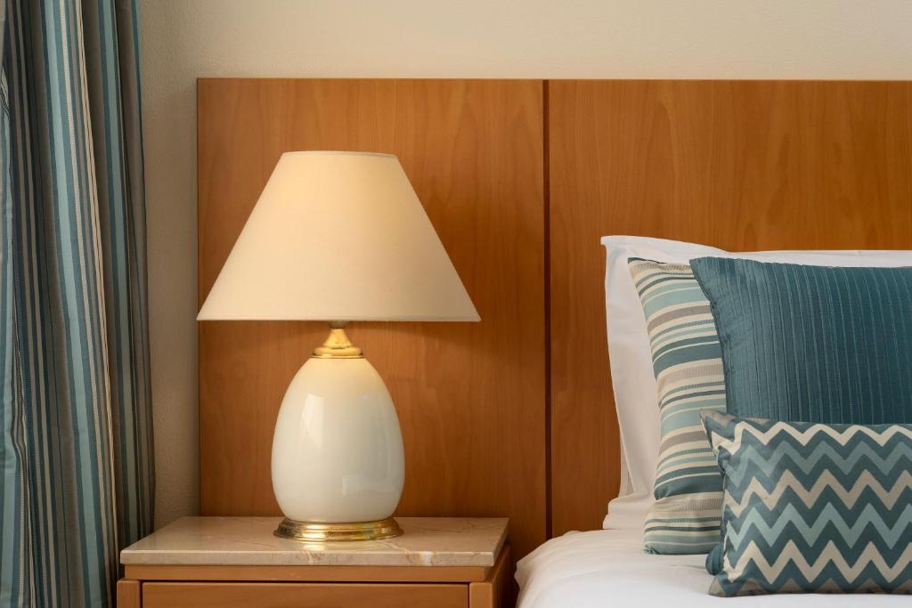 a lamp on a night stand next to a bed at Interpass Vau Hotel Apartamentos in Portimão