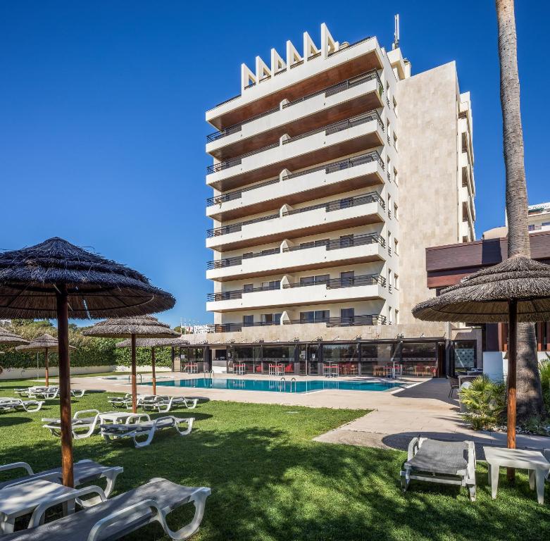 a hotel with a lawn with chairs and umbrellas at Interpass Vau Hotel Apartamentos in Portimão