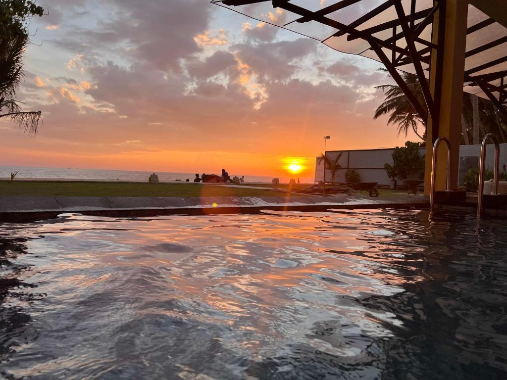 a swimming pool with the sunset in the background at Amanda Beach Villas in Unawatuna