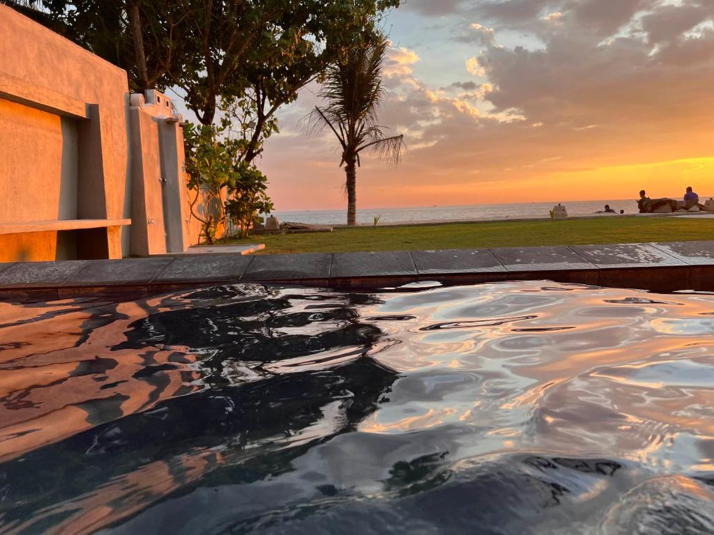 a swimming pool with a sunset in the background at Amanda Beach Villas in Unawatuna