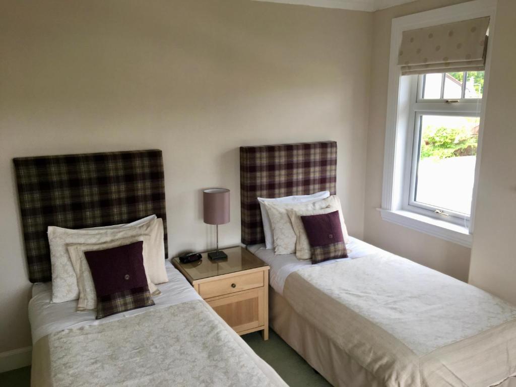 1 dormitorio con 2 camas y ventana en The Gatehouse B&B, en Inverness