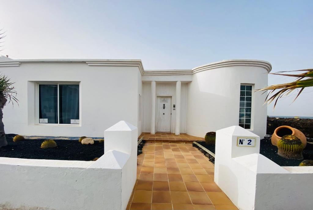 a house with white walls and a courtyard with vases at Mision Costa in Corralejo