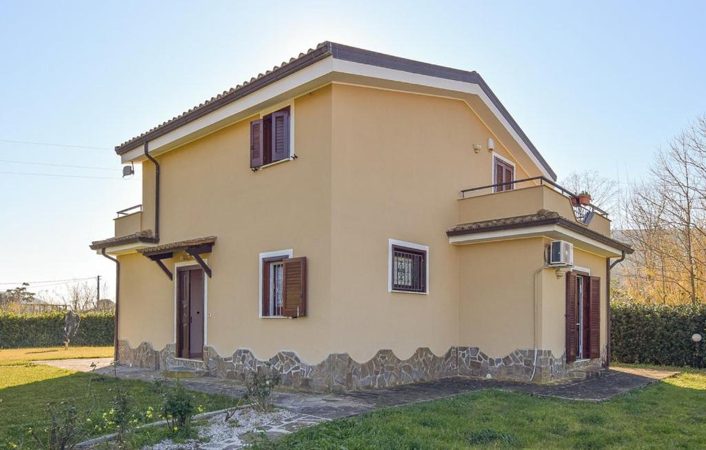 a small yellow house with brown shuttered windows at VILLA ROGE' in Castellabate